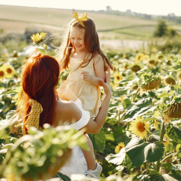 Mother with daughyer in a field. Sunflowers field. Family in a cute clothes